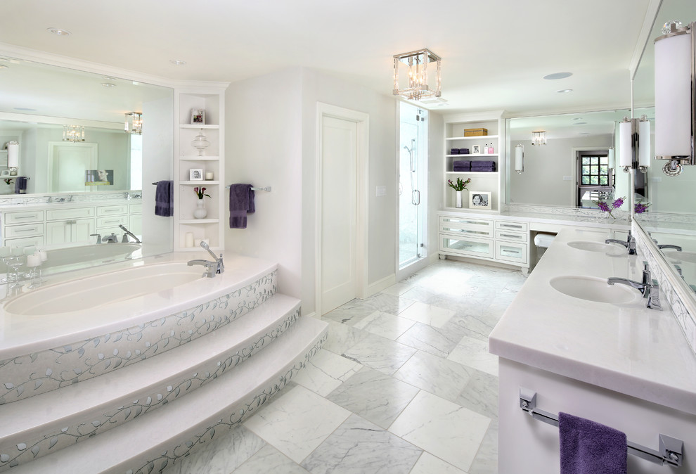 Пример оригинального дизайна: большая главная ванная комната в стиле неоклассика (современная классика) с врезной раковиной, белыми фасадами, мраморной столешницей, полновстраиваемой ванной, белой плиткой, зеркальной плиткой, серыми стенами, мраморным полом и стеклянными фасадами