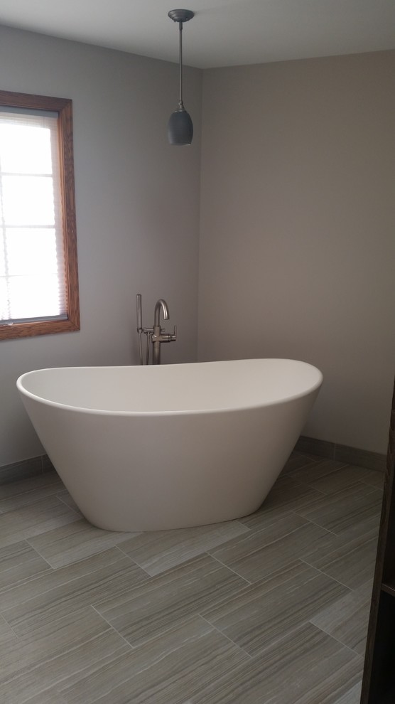 Photo of a large contemporary ensuite bathroom in Chicago with shaker cabinets, medium wood cabinets, a freestanding bath, a double shower, a two-piece toilet, grey tiles, porcelain tiles, grey walls, porcelain flooring, a submerged sink and granite worktops.