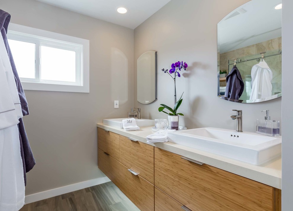 Example of a mid-sized trendy master beige tile and travertine tile porcelain tile and brown floor bathroom design in Los Angeles with flat-panel cabinets, light wood cabinets, a two-piece toilet, beige walls, a vessel sink and quartz countertops