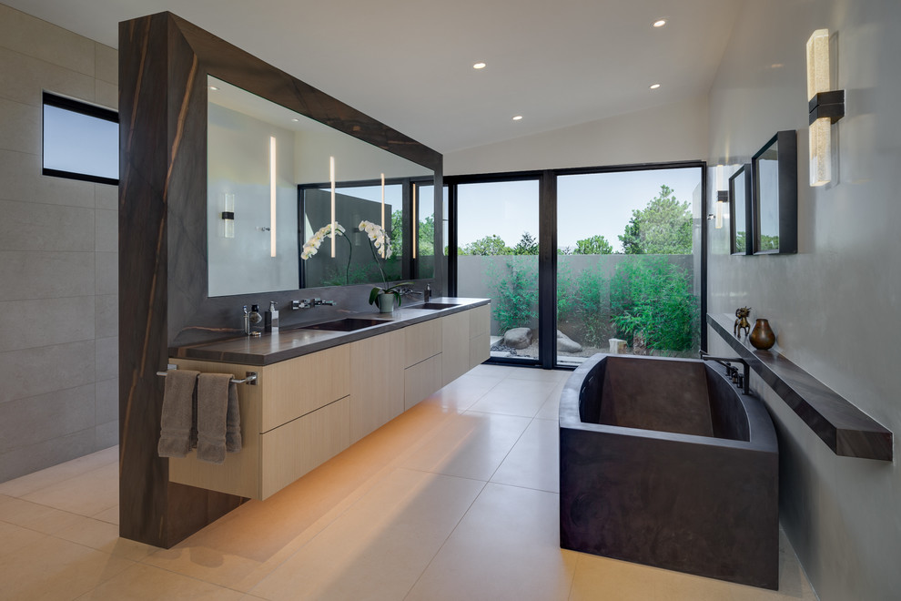 Modernes Badezimmer mit flächenbündigen Schrankfronten, hellen Holzschränken, freistehender Badewanne, grauer Wandfarbe, beigem Boden und grauer Waschtischplatte in Sonstige