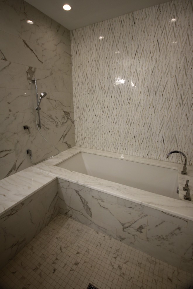 Aménagement d'une salle de bain principale classique de taille moyenne avec un placard avec porte à panneau encastré, des portes de placard beiges, une baignoire encastrée, un combiné douche/baignoire, un carrelage gris, du carrelage en marbre, un mur gris, un sol en marbre, un lavabo encastré, un plan de toilette en marbre, un sol blanc, une cabine de douche à porte battante et un plan de toilette blanc.