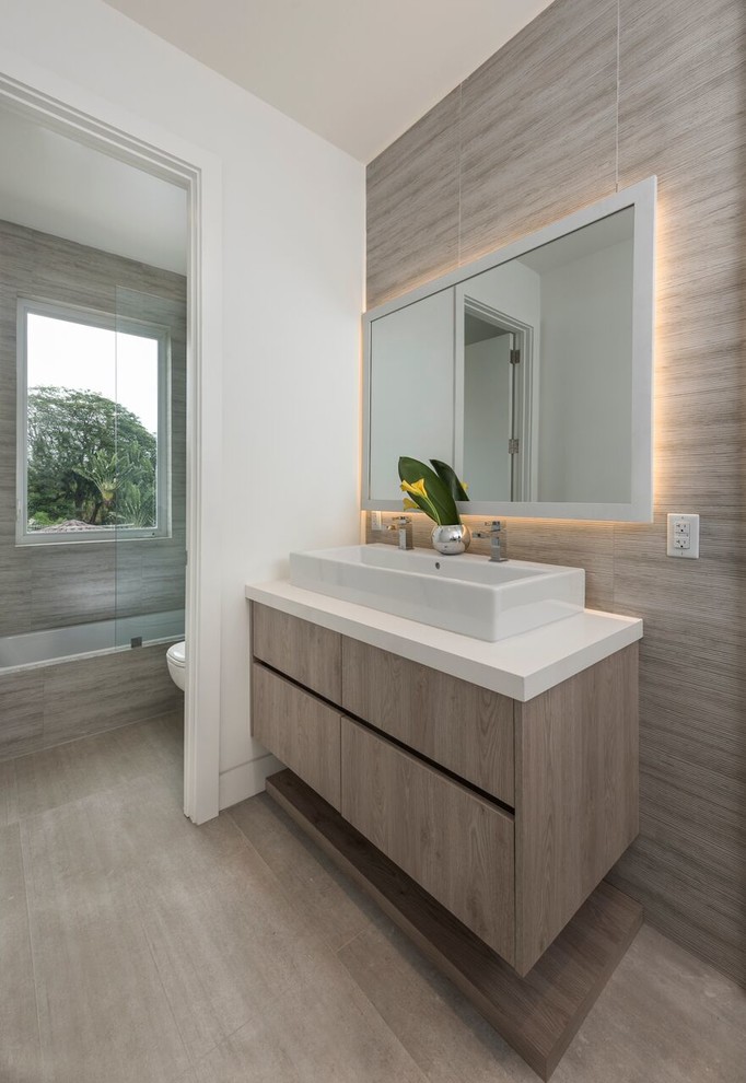 Example of a mid-sized trendy master beige floor and porcelain tile bathroom design in Miami with white walls, a vessel sink, a hinged shower door, flat-panel cabinets, light wood cabinets and quartz countertops