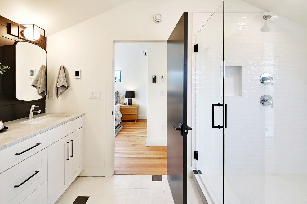 This is an example of a medium sized contemporary ensuite bathroom in Seattle with recessed-panel cabinets, white cabinets, a corner shower, white tiles, ceramic tiles, a built-in sink, marble worktops, a hinged door, grey worktops, double sinks and a built in vanity unit.