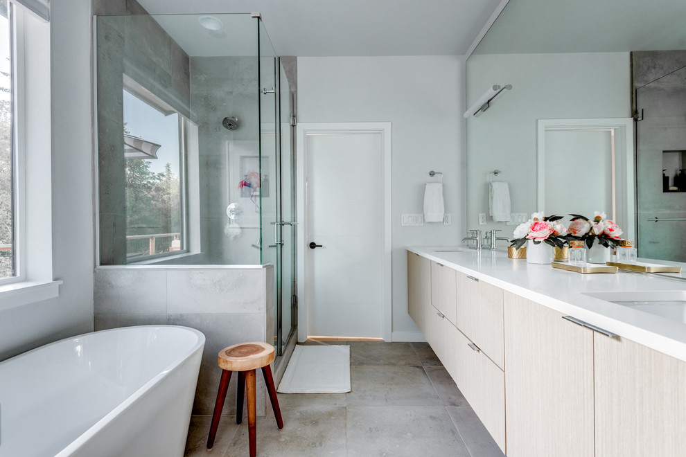 This is an example of a contemporary bathroom in Portland with flat-panel cabinets, beige cabinets, a freestanding bath, a corner shower, grey tiles, white walls, a submerged sink, grey floors, a hinged door and white worktops.