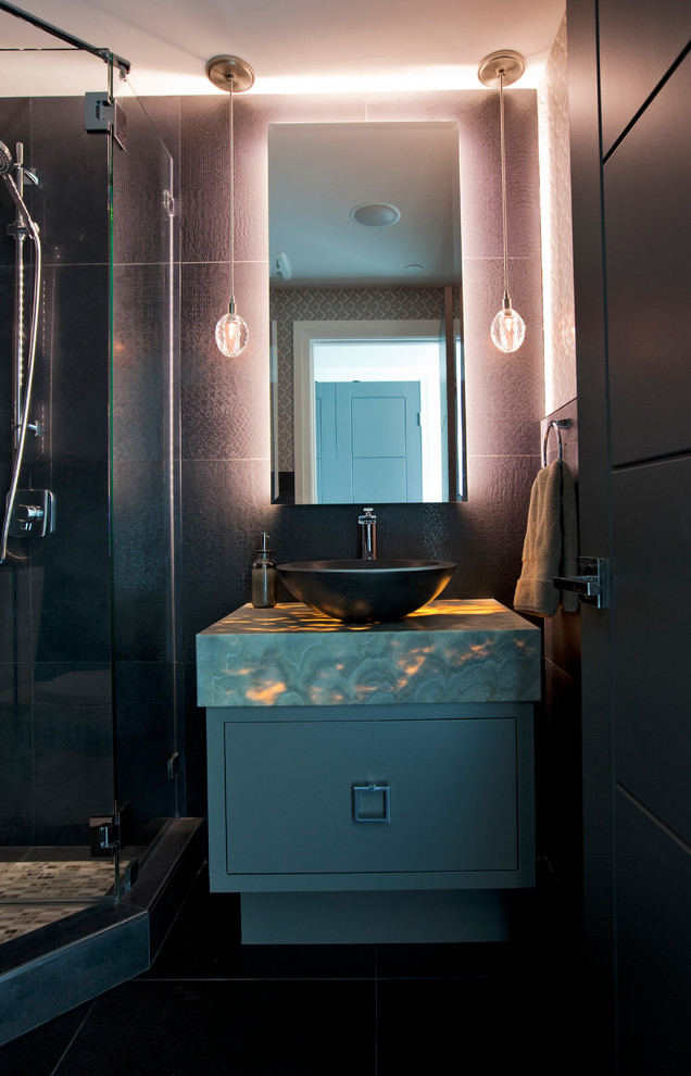 На фото: ванная комната среднего размера в современном стиле с настольной раковиной, плоскими фасадами, серыми фасадами, столешницей из оникса, раздельным унитазом, черной плиткой, керамогранитной плиткой, черными стенами и полом из керамогранита с