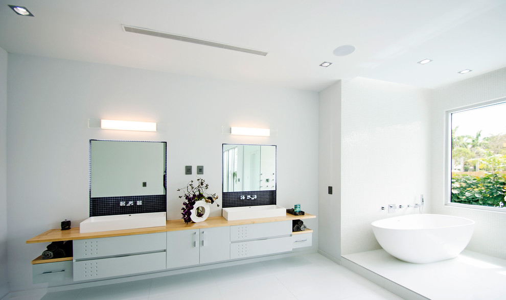 Idée de décoration pour une très grande salle de bain principale minimaliste avec un placard en trompe-l'oeil, des portes de placard grises, une baignoire indépendante, un espace douche bain, un sol en carrelage de porcelaine, une vasque, un plan de toilette en bois, un sol blanc et un plan de toilette marron.