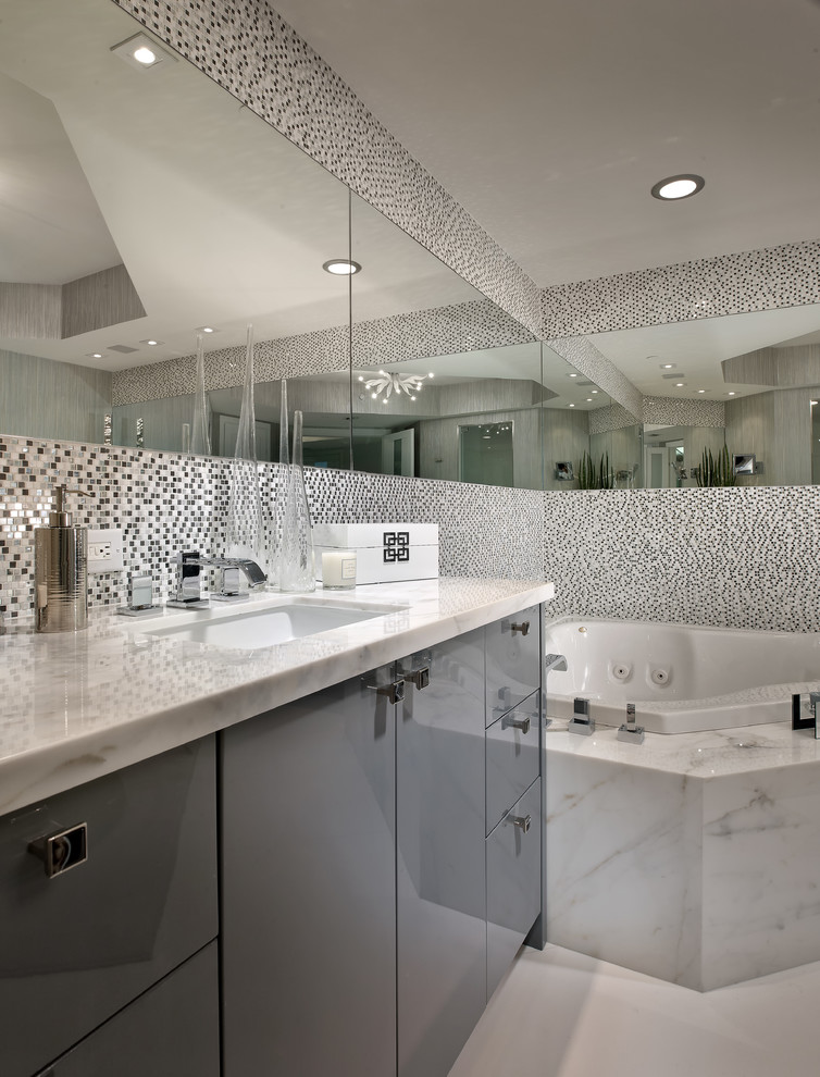 Diseño de cuarto de baño actual con armarios con paneles lisos, puertas de armario grises, bañera esquinera, ducha doble y baldosas y/o azulejos blancos