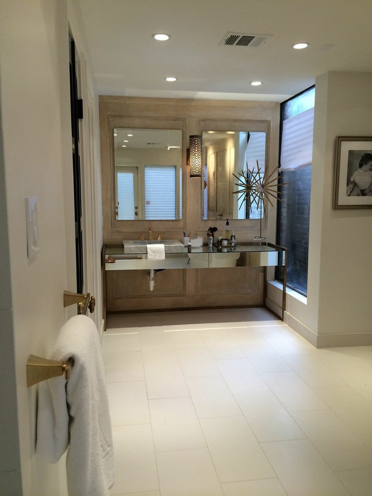 Пример оригинального дизайна: большая главная ванная комната в стиле модернизм с настольной раковиной, белой плиткой, белыми стенами, стеклянными фасадами, отдельно стоящей ванной, двойным душем, раздельным унитазом, керамогранитной плиткой, полом из керамогранита, стеклянной столешницей, белым полом, душем с распашными дверями, сиденьем для душа, тумбой под одну раковину, напольной тумбой и панелями на части стены