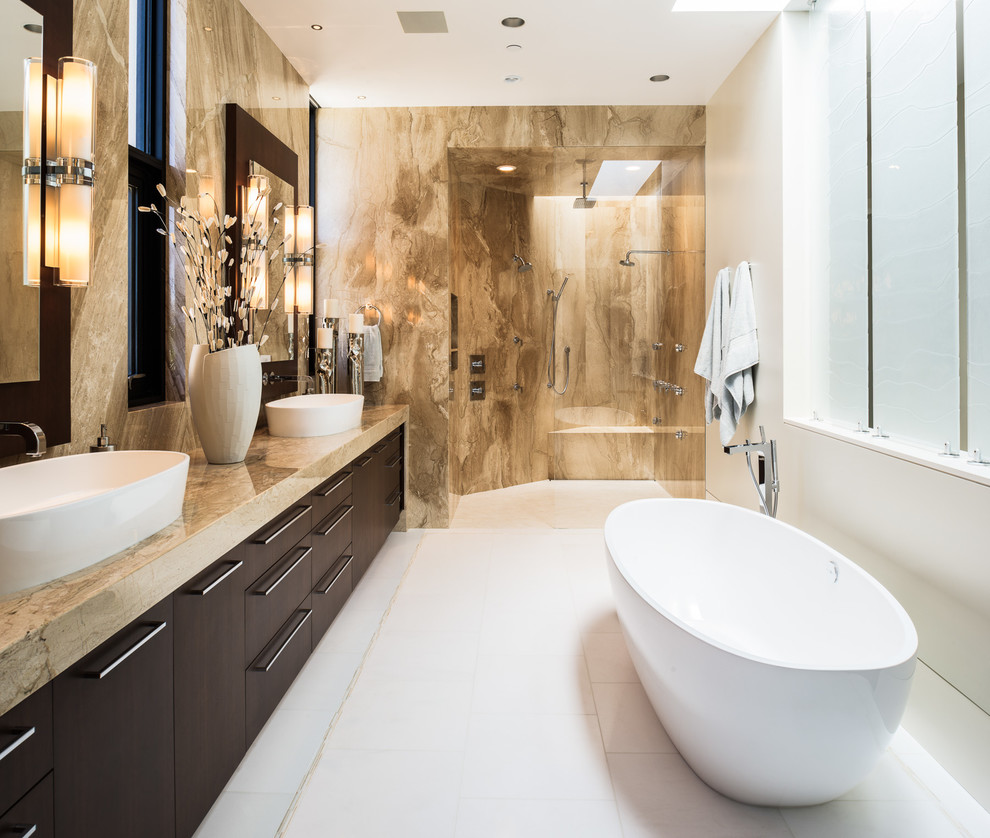 На фото: ванная комната в современном стиле с настольной раковиной, плоскими фасадами, темными деревянными фасадами, отдельно стоящей ванной, душем в нише, коричневой плиткой, белыми стенами и бежевой столешницей с