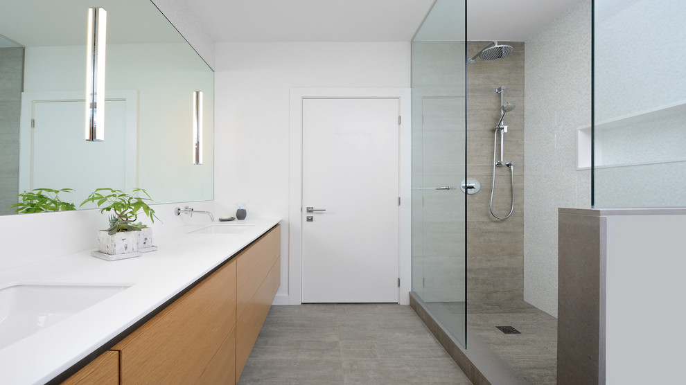 This is an example of a medium sized modern ensuite bathroom in Toronto with flat-panel cabinets, light wood cabinets, a freestanding bath, a corner shower, a one-piece toilet, white tiles, ceramic tiles, white walls, porcelain flooring, a submerged sink and solid surface worktops.