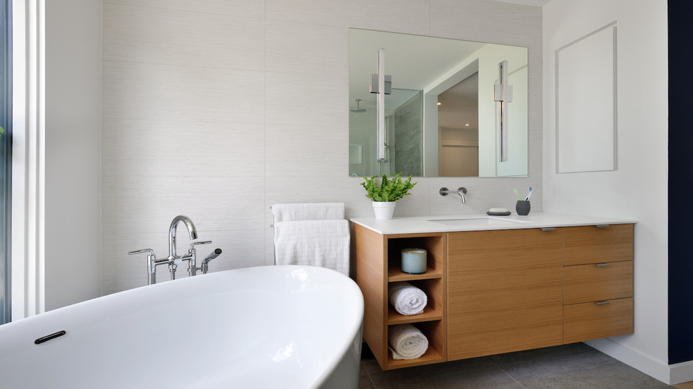 Mid-sized minimalist master white tile and ceramic tile porcelain tile and gray floor bathroom photo in Toronto with flat-panel cabinets, light wood cabinets, a one-piece toilet, white walls, an undermount sink and solid surface countertops