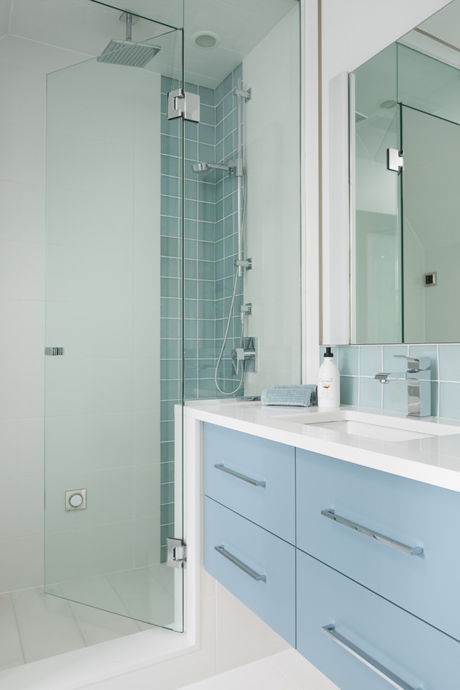 Kleines Modernes Badezimmer mit flächenbündigen Schrankfronten, blauen Schränken, Porzellan-Bodenfliesen, Unterbauwaschbecken, weißem Boden, Falttür-Duschabtrennung, Eckdusche und weißer Wandfarbe in Vancouver