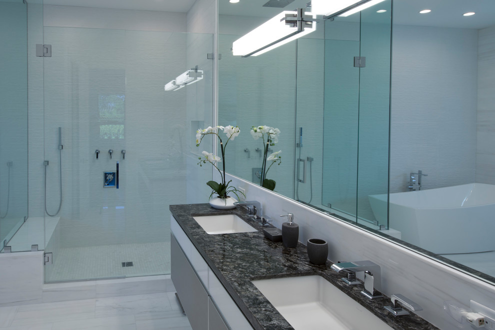 Exemple d'une salle de bain principale tendance de taille moyenne avec un placard à porte plane, des portes de placard marrons, une baignoire indépendante, une douche d'angle, un carrelage gris, un mur gris, un lavabo suspendu et un sol blanc.