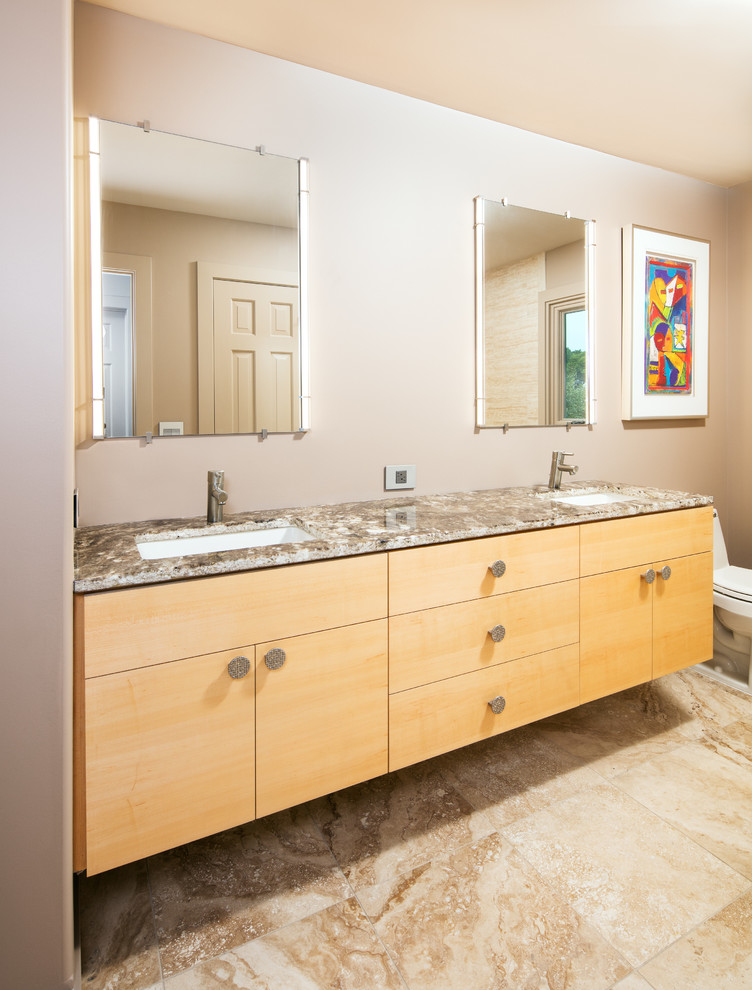 Example of a mid-sized trendy master travertine floor bathroom design in Omaha with flat-panel cabinets, light wood cabinets, an undermount sink, granite countertops, a one-piece toilet and beige walls