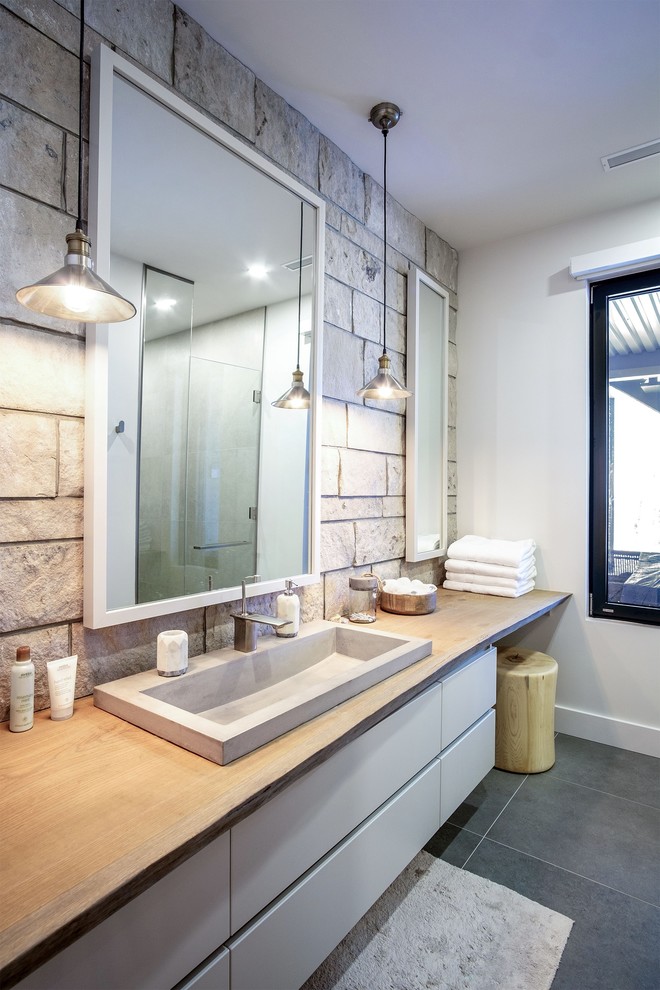 Foto di una stanza da bagno rustica con ante lisce, ante bianche, piastrelle grigie, piastrelle in pietra, lavabo a bacinella, top in legno, pavimento grigio e top beige