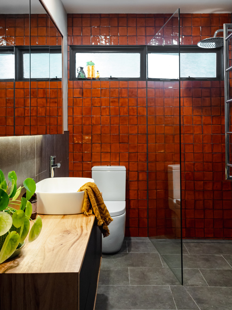 This is an example of a small contemporary ensuite bathroom in Melbourne with flat-panel cabinets, medium wood cabinets, a walk-in shower, a one-piece toilet, grey tiles, porcelain tiles, grey walls, porcelain flooring, a vessel sink, wooden worktops, grey floors, an open shower, a wall niche, a single sink and a floating vanity unit.