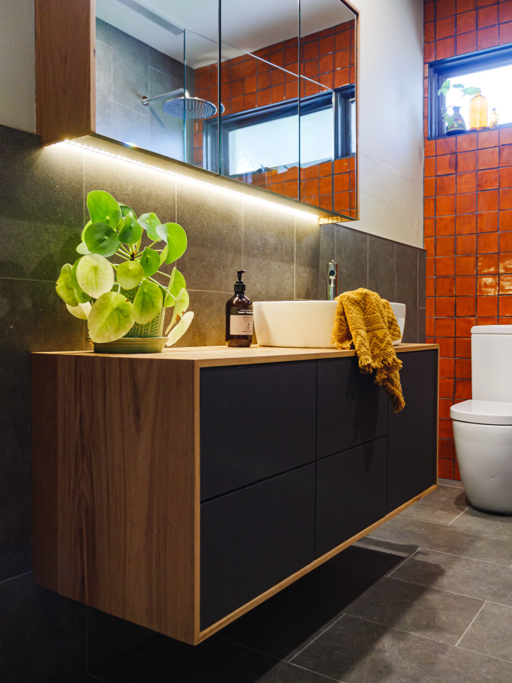 Bathroom - small contemporary master gray tile and porcelain tile porcelain tile, gray floor and single-sink bathroom idea in Melbourne with flat-panel cabinets, medium tone wood cabinets, a one-piece toilet, gray walls, a vessel sink, wood countertops, a niche and a floating vanity