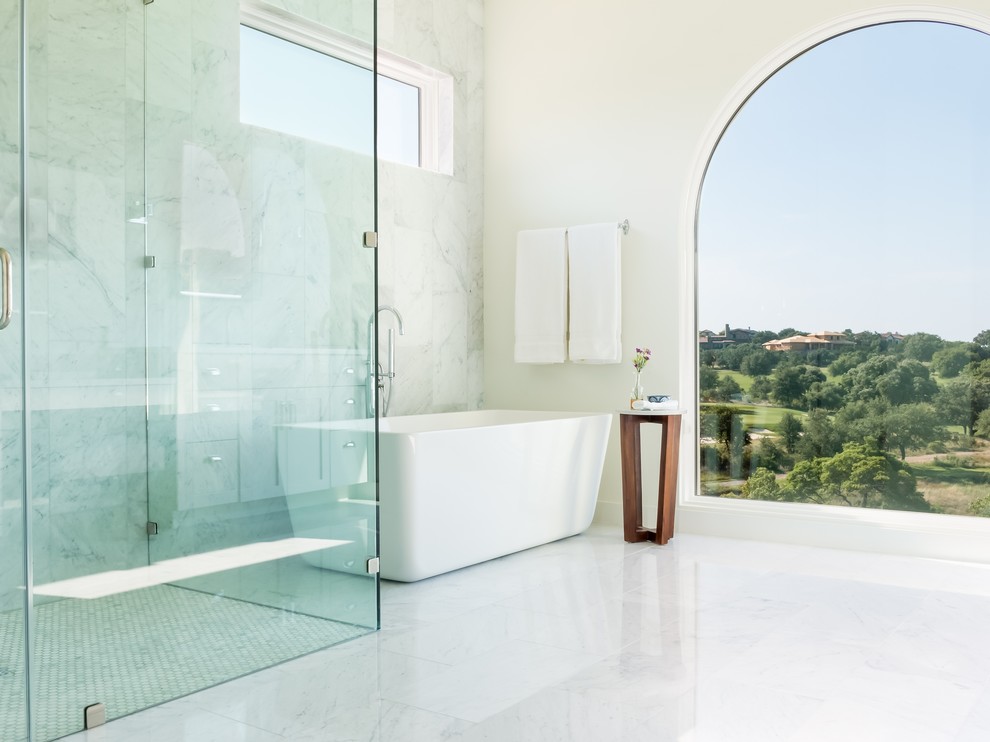 Mediterranes Badezimmer mit freistehender Badewanne, bodengleicher Dusche, weißen Fliesen, weißer Wandfarbe, weißem Boden und Falttür-Duschabtrennung in Austin
