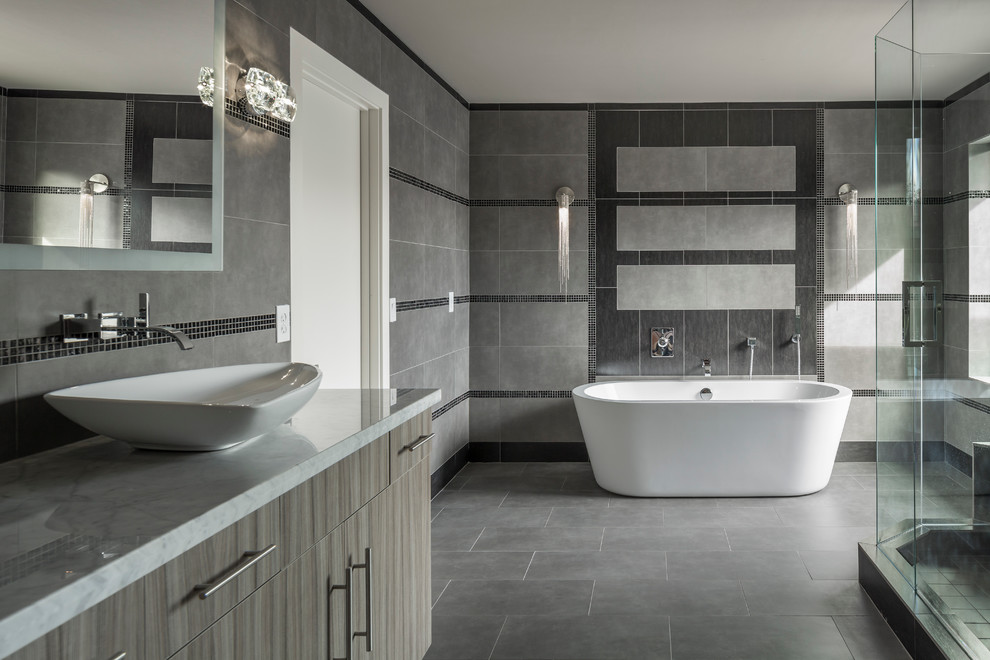 Example of a large trendy master gray tile and porcelain tile porcelain tile bathroom design in Phoenix with a vessel sink, flat-panel cabinets, gray cabinets, marble countertops, a one-piece toilet and gray walls
