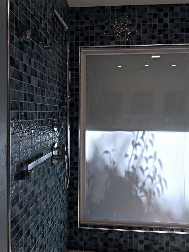 На фото: главная ванная комната в современном стиле с плоскими фасадами, темными деревянными фасадами, синей плиткой, плиткой из листового стекла, полом из керамической плитки, раковиной с несколькими смесителями и столешницей из кварцита с