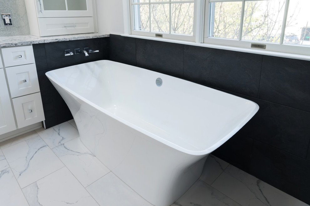 Photo of a medium sized contemporary ensuite bathroom in Philadelphia with shaker cabinets, white cabinets, a freestanding bath, an alcove shower, a two-piece toilet, black tiles, glass sheet walls, grey walls, porcelain flooring, a submerged sink, engineered stone worktops, white floors, a hinged door and multi-coloured worktops.