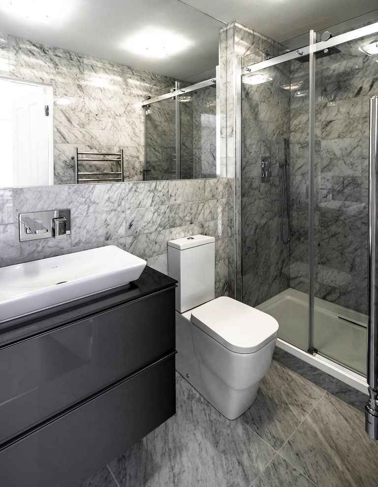 Small contemporary shower room bathroom in Other with a vessel sink, grey cabinets, glass worktops, an alcove shower, a two-piece toilet, white tiles, stone tiles, white walls, marble flooring and flat-panel cabinets.
