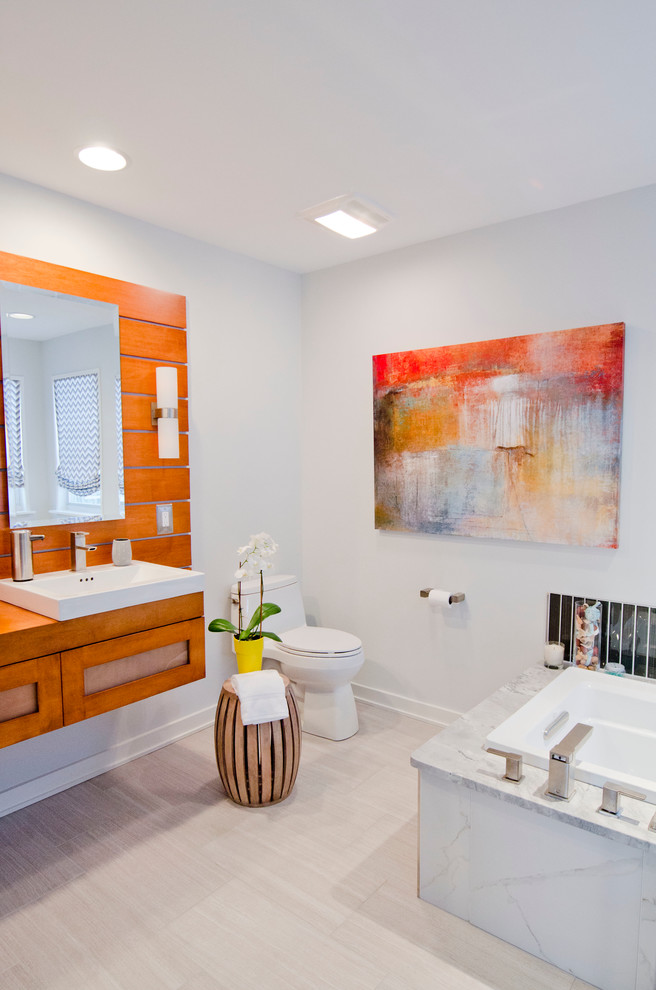 Modernes Badezimmer mit Wandwaschbecken, orangefarbenen Schränken, Waschtisch aus Holz, freistehender Badewanne, offener Dusche und Toilette mit Aufsatzspülkasten in Philadelphia
