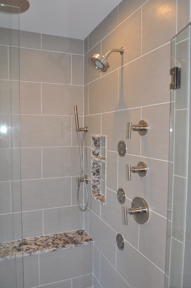This is an example of a modern bathroom in Boston with a submerged sink, freestanding cabinets, medium wood cabinets, granite worktops, a freestanding bath, a built-in shower, a two-piece toilet and grey tiles.