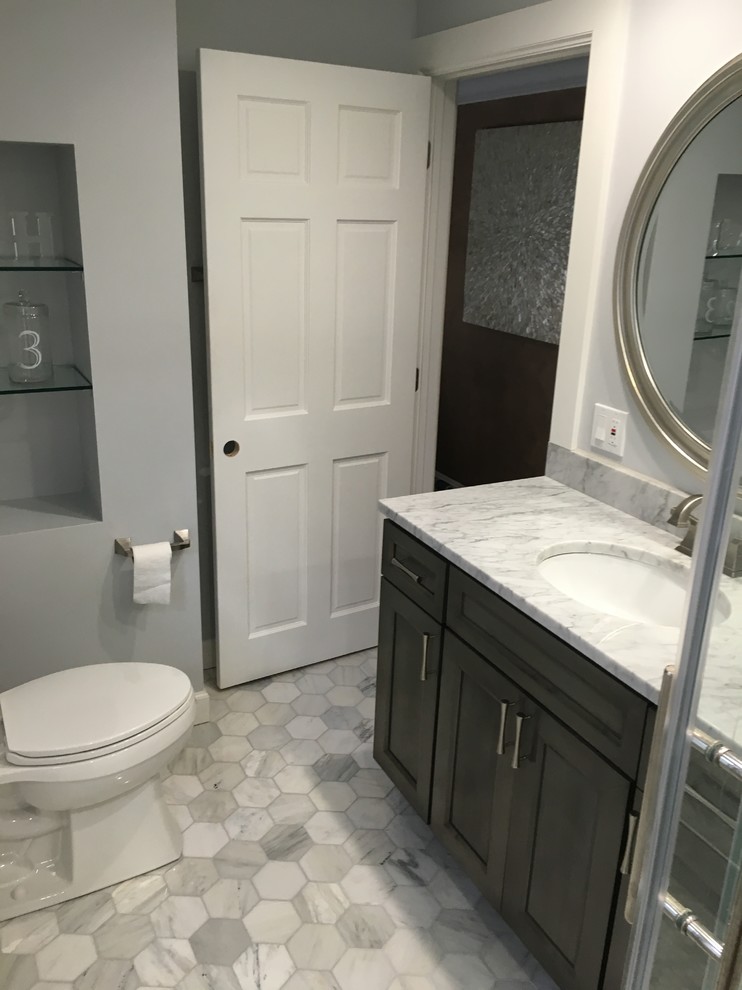 Klassisches Badezimmer mit flächenbündigen Schrankfronten, grauen Schränken, Duschnische, beigen Fliesen, Porzellanfliesen, weißer Wandfarbe, Keramikboden, integriertem Waschbecken und Mineralwerkstoff-Waschtisch in Milwaukee