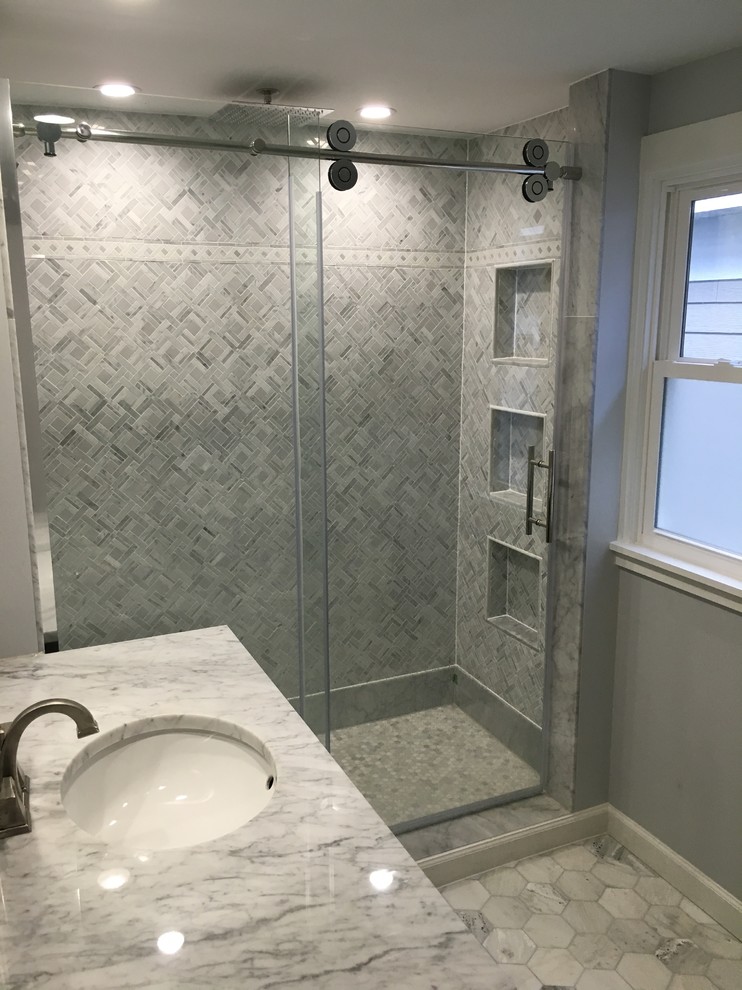 Design ideas for a traditional bathroom in Milwaukee with flat-panel cabinets, grey cabinets, an alcove shower, beige tiles, porcelain tiles, white walls, ceramic flooring, an integrated sink and solid surface worktops.