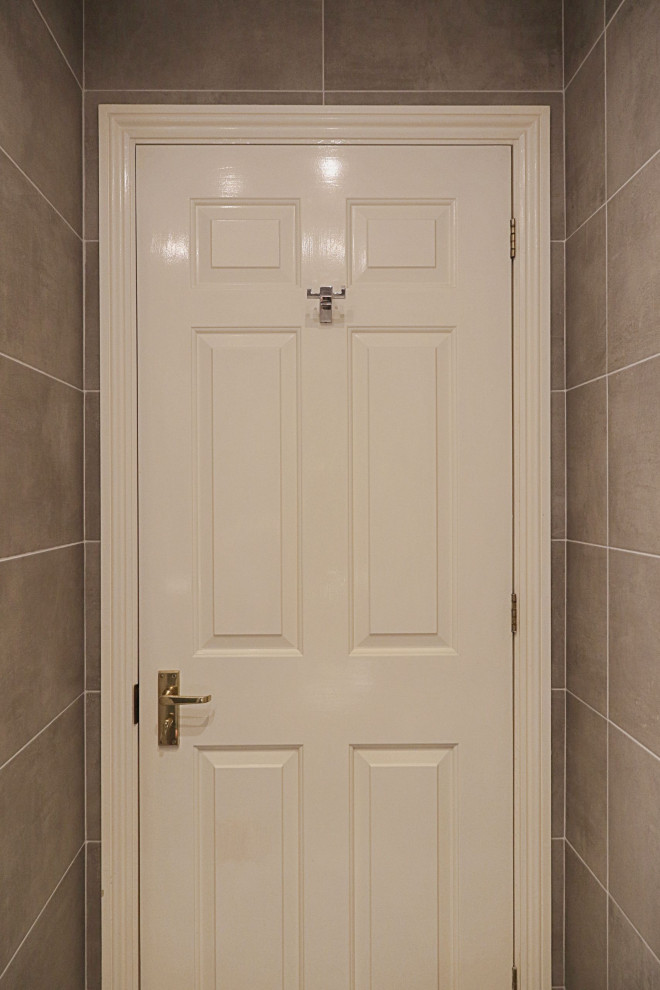 Idéer för mellanstora funkis en-suite badrum, med släta luckor, bruna skåp, en kantlös dusch, grå kakel, porslinskakel, grå väggar, klinkergolv i porslin, ett väggmonterat handfat, grått golv och dusch med gångjärnsdörr