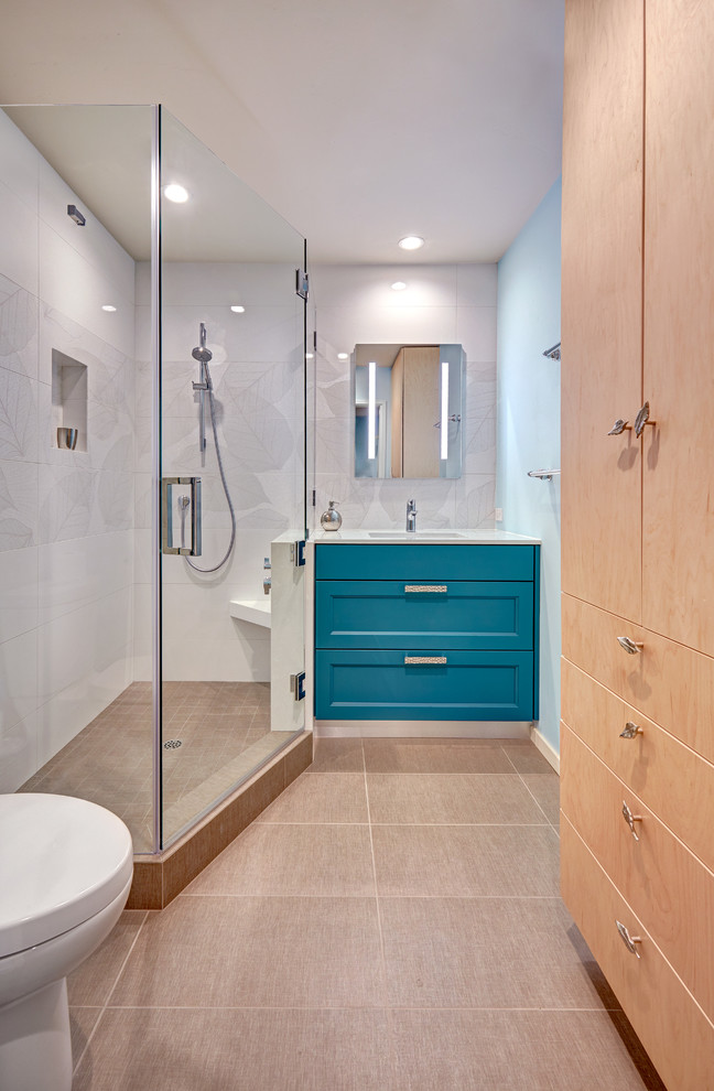 Idéer för små funkis badrum med dusch, med släta luckor, blå skåp, en hörndusch, en toalettstol med hel cisternkåpa, vit kakel, porslinskakel, blå väggar, klinkergolv i porslin, ett undermonterad handfat, bänkskiva i kvarts, beiget golv och dusch med gångjärnsdörr