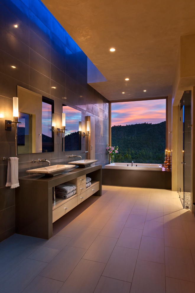 Inspiration for a large modern ensuite bathroom in Albuquerque with open cabinets, light wood cabinets, an alcove bath, a built-in shower, grey tiles, grey walls, porcelain flooring, a vessel sink and concrete worktops.