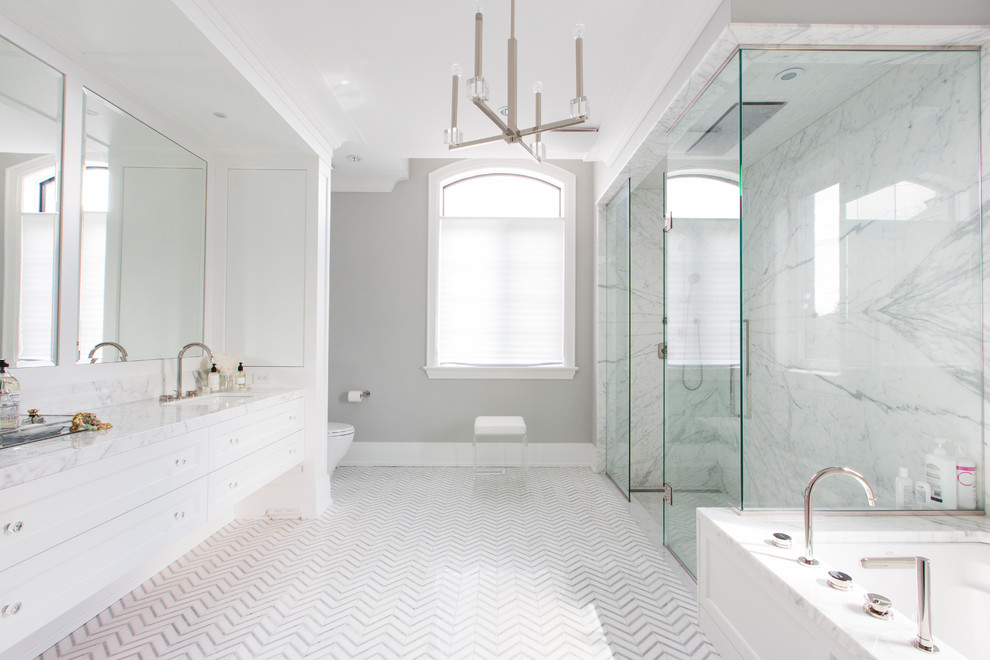 Exemple d'une grande salle de bain principale tendance avec un placard à porte shaker, des portes de placard blanches, une baignoire encastrée, une douche à l'italienne, un carrelage gris, un carrelage blanc, du carrelage en marbre, un mur gris, un sol en carrelage de porcelaine, un lavabo encastré, un plan de toilette en marbre, un sol multicolore et une cabine de douche à porte battante.