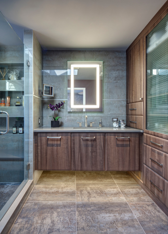 Modelo de cuarto de baño contemporáneo con lavabo bajoencimera, armarios con paneles lisos, puertas de armario de madera en tonos medios y baldosas y/o azulejos grises