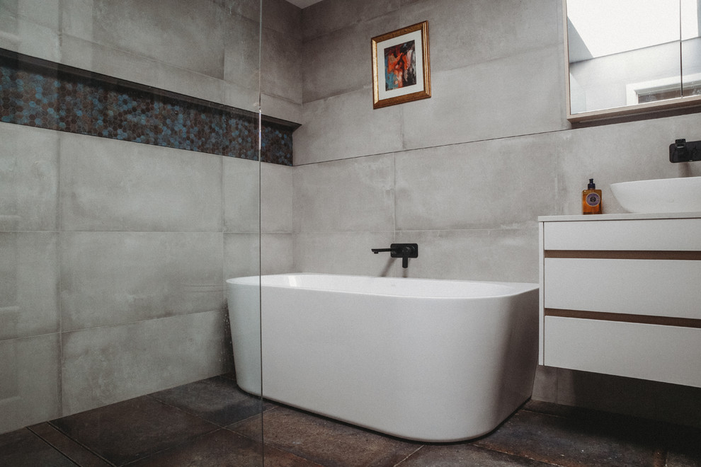 Design ideas for a medium sized contemporary bathroom in Canberra - Queanbeyan with flat-panel cabinets, white cabinets, a freestanding bath, a walk-in shower, a one-piece toilet, grey tiles, cement tiles, grey walls, ceramic flooring, a vessel sink, engineered stone worktops, grey floors and an open shower.