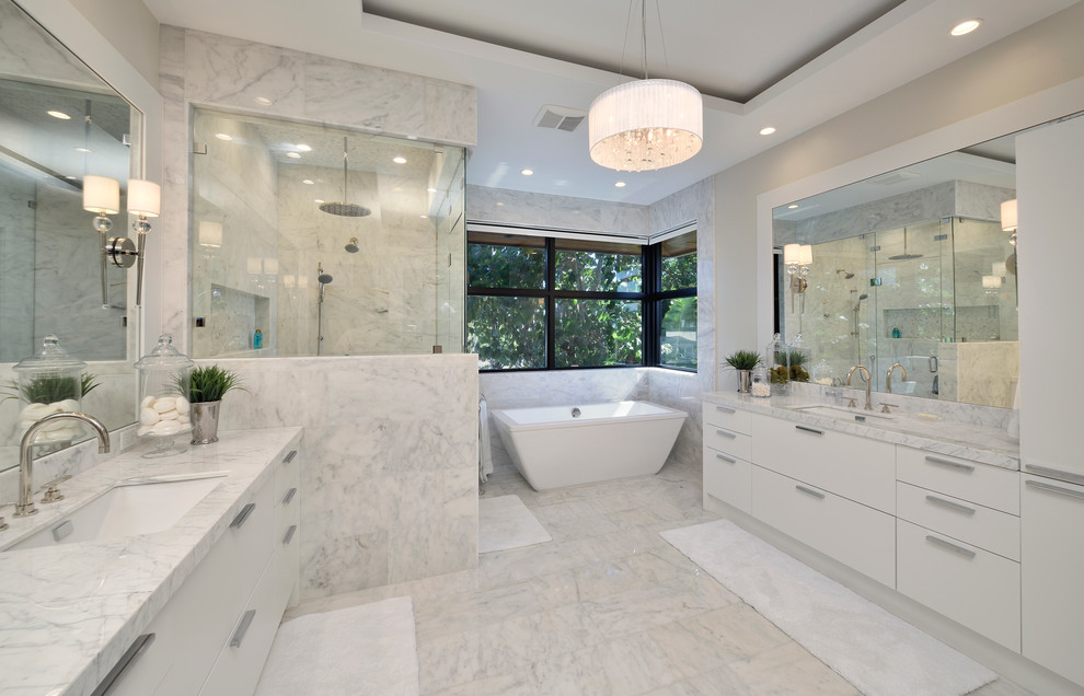 Foto de cuarto de baño contemporáneo con lavabo bajoencimera, armarios con paneles lisos, puertas de armario blancas, bañera exenta, ducha esquinera, baldosas y/o azulejos blancos y paredes grises