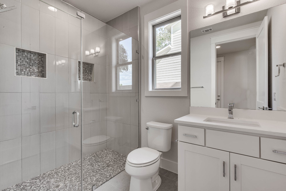 Идея дизайна: ванная комната среднего размера в современном стиле с фасадами в стиле шейкер, белыми фасадами, душем в нише, унитазом-моноблоком, белой плиткой, серыми стенами, полом из керамогранита, душевой кабиной, врезной раковиной, столешницей из искусственного кварца, серым полом, душем с распашными дверями и белой столешницей