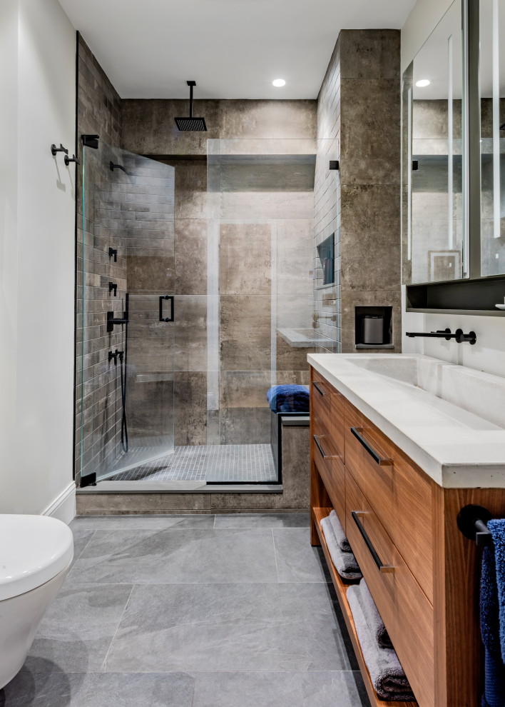 Inspiration for a medium sized contemporary shower room bathroom in Boston with a hinged door, flat-panel cabinets, medium wood cabinets, an alcove shower, brown tiles, grey tiles, white walls, a trough sink, grey floors, white worktops, a shower bench, double sinks and a freestanding vanity unit.