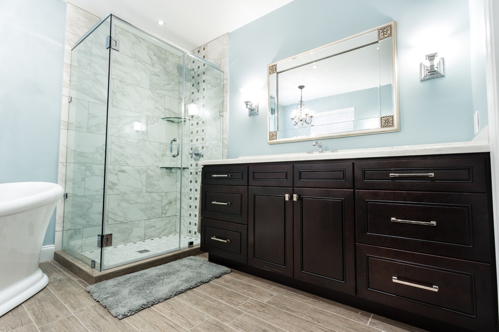 Design ideas for a large contemporary ensuite bathroom in Miami with shaker cabinets, dark wood cabinets, engineered stone worktops, a freestanding bath, a corner shower, a one-piece toilet, multi-coloured tiles, porcelain tiles, blue walls and porcelain flooring.