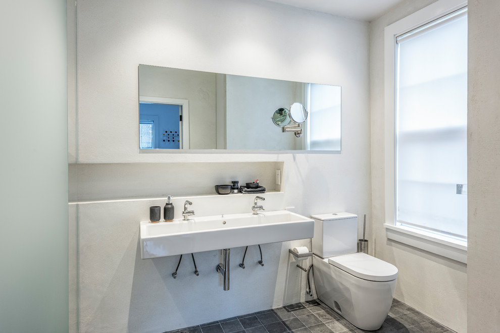 Foto de cuarto de baño actual con sanitario de dos piezas, paredes blancas, suelo de pizarra, lavabo suspendido y suelo gris