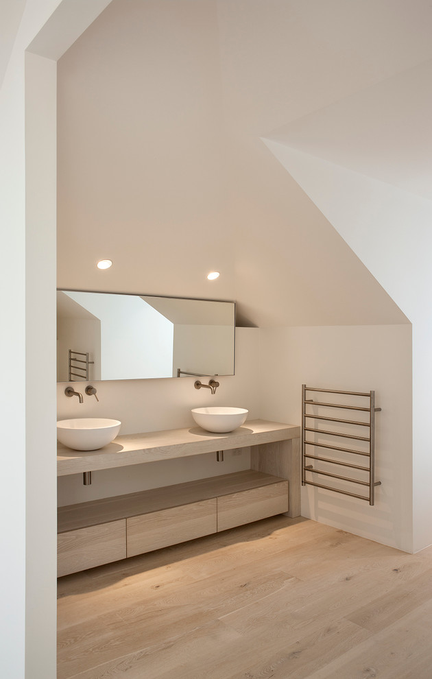 На фото: ванная комната в современном стиле с настольной раковиной, плоскими фасадами, светлыми деревянными фасадами, белыми стенами и светлым паркетным полом с