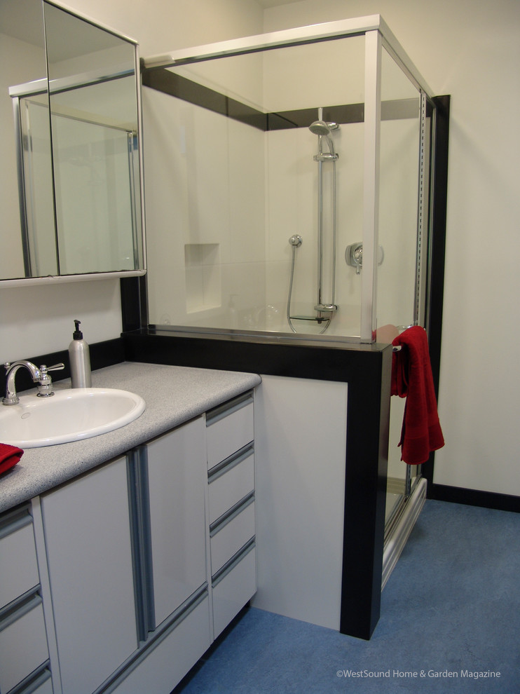 Foto på ett mellanstort vintage grå badrum för barn, med ett nedsänkt handfat, släta luckor, vita skåp, bänkskiva i akrylsten, vita väggar, linoleumgolv, en dusch i en alkov, blått golv och dusch med gångjärnsdörr