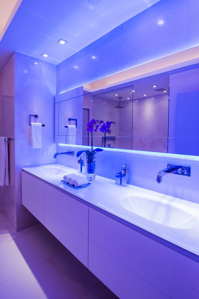 Пример оригинального дизайна: огромная главная ванная комната в стиле модернизм с плоскими фасадами, белыми фасадами, открытым душем, унитазом-моноблоком, белой плиткой, каменной плиткой, бежевыми стенами, полом из известняка, монолитной раковиной и стеклянной столешницей