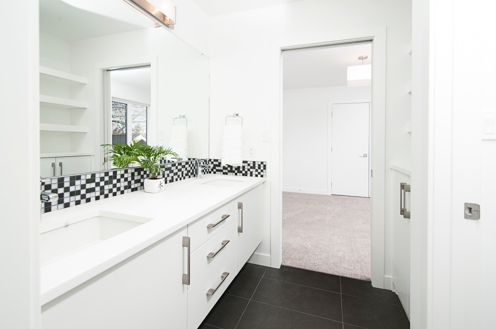 Klassisk inredning av ett mellanstort vit vitt en-suite badrum, med släta luckor, vita skåp, ett japanskt badkar, en dusch/badkar-kombination, en toalettstol med hel cisternkåpa, vit kakel, keramikplattor, vita väggar, klinkergolv i keramik, ett väggmonterat handfat, granitbänkskiva och grått golv