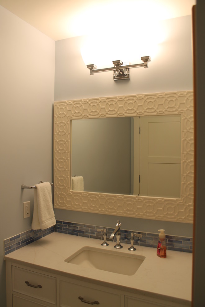 Réalisation d'une salle de bain marine avec des portes de placard blanches, un mur bleu et un plan de toilette blanc.