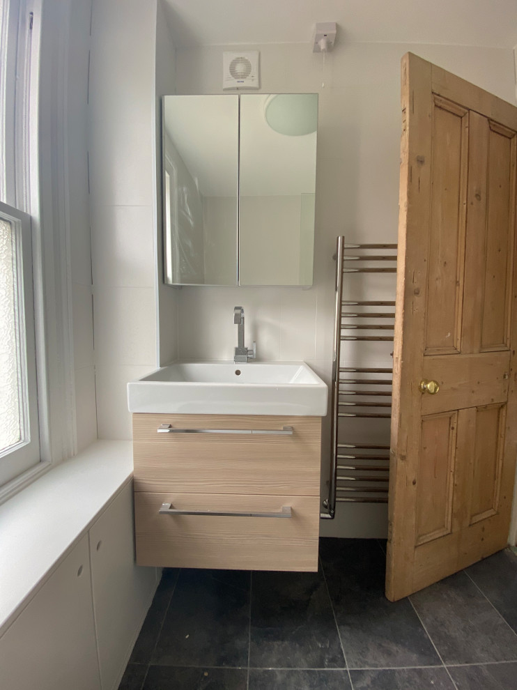 На фото: детская ванная комната среднего размера в современном стиле с коричневыми фасадами, душем над ванной, белой плиткой, полом из керамогранита, серым полом, тумбой под одну раковину и подвесной тумбой с