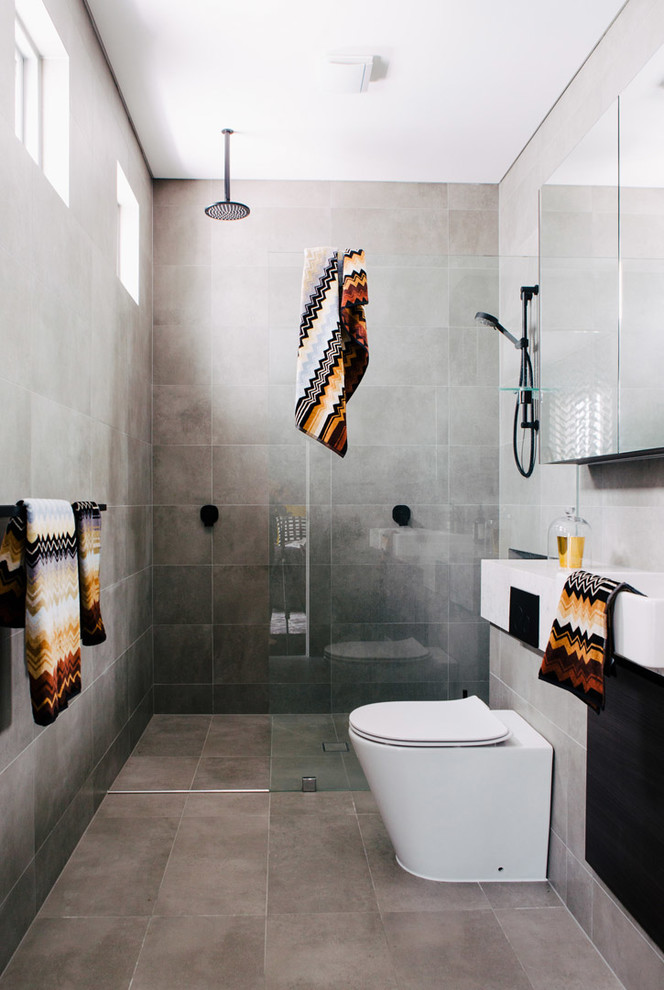 Imagen de cuarto de baño actual con ducha empotrada, sanitario de una pieza, paredes grises, baldosas y/o azulejos grises, baldosas y/o azulejos de cemento, aseo y ducha, lavabo suspendido, suelo gris y ducha abierta