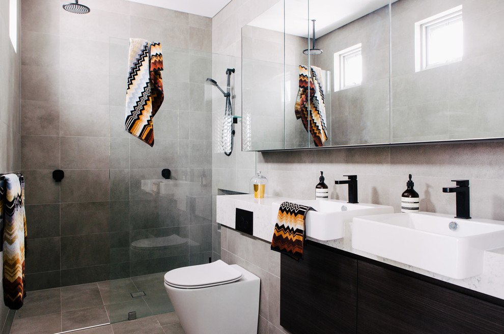 Idées déco pour une douche en alcôve contemporaine avec un placard à porte plane, des portes de placard noires, une baignoire indépendante, WC à poser, un carrelage gris, des carreaux de béton, un mur gris et un plan de toilette en marbre.