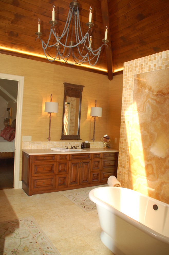 Пример оригинального дизайна: большая ванная комната в стиле фьюжн с накладной раковиной, фасадами с выступающей филенкой, столешницей из известняка, отдельно стоящей ванной, угловым душем, бежевыми стенами и полом из травертина